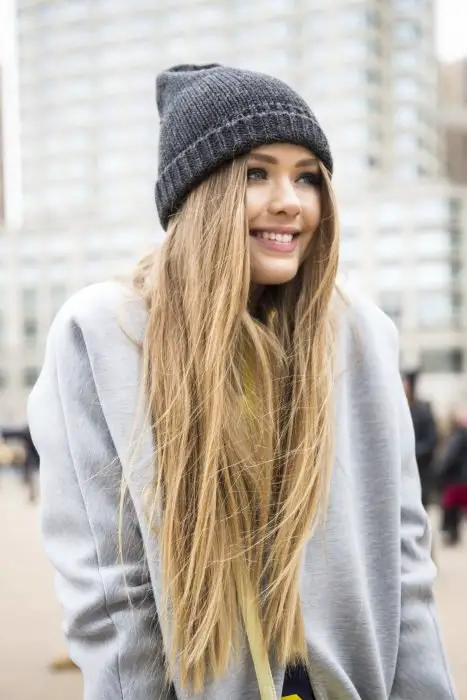 Garota de cabelos loiros compridos com boné e moletom de inverno