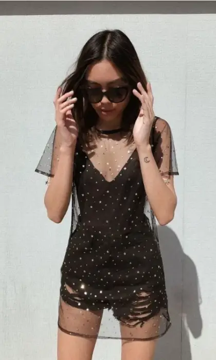 Menina com óculos de sol com vestido preto com transparências de estrelas