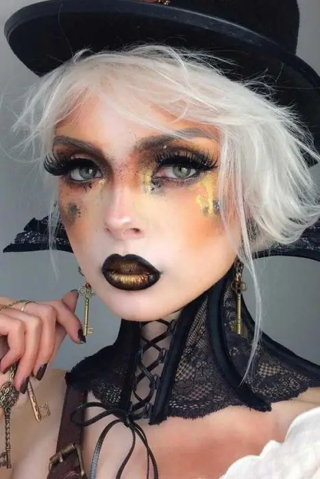 Garota com maquiagem em tons laranja e glitter simulando uma boa bruxa