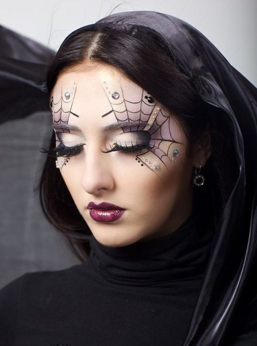 Menina mostrando a maquiagem com teias de aranha nos olhos
