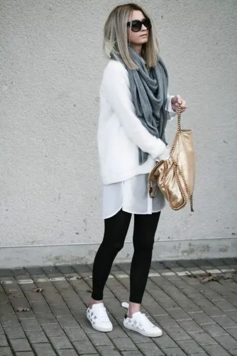 Menina com lenço longo cinza, suéter branco folgado e legging preta