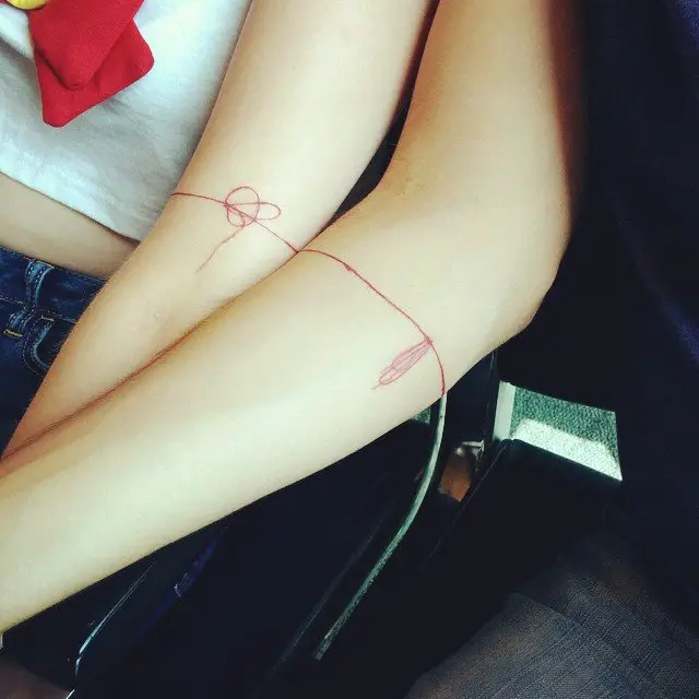 Braços com tatuagem de fio vermelho 
