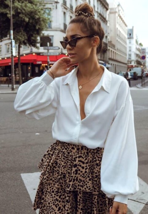 Conjunto com blusa branca;  mulher na rua, estilo retro, óculos triangulares, coque alto, saia com estampa animal