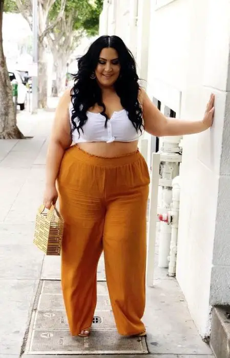 mulher com calça laranja de top branco 