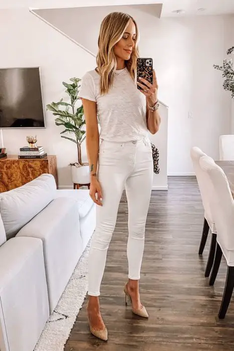 Mulher loira tirando selfie em frente ao espelho com roupa branca