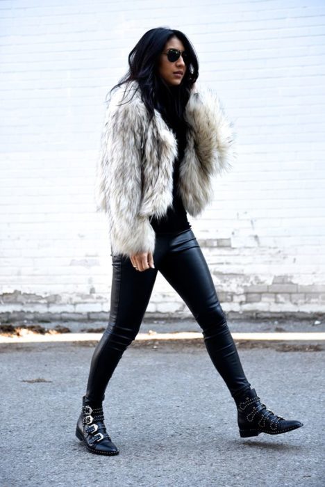 Menina andando com calça de couro preta e jaqueta de pele branca