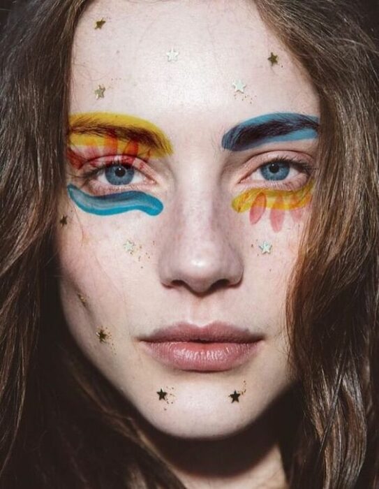 Maquiagem estética em tons de azul, amarelo e vermelho