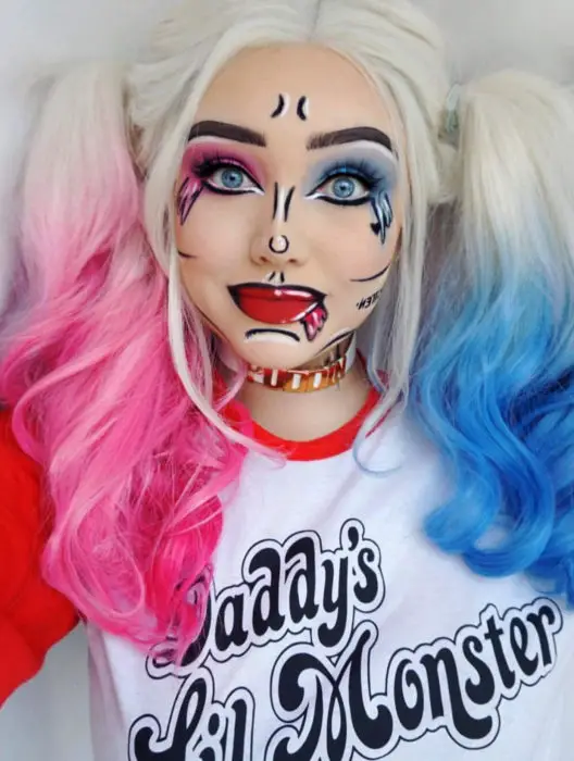 Traje de Halloween da arte pop em quadrinhos;  garota loira de olhos azuis com penteado pigtail, estilo cartoon composta pela vilã Harley Quinn com cabelo azul e rosa