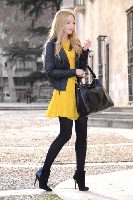 Menina com um vestido amarelo com meia-calça preta e botins 