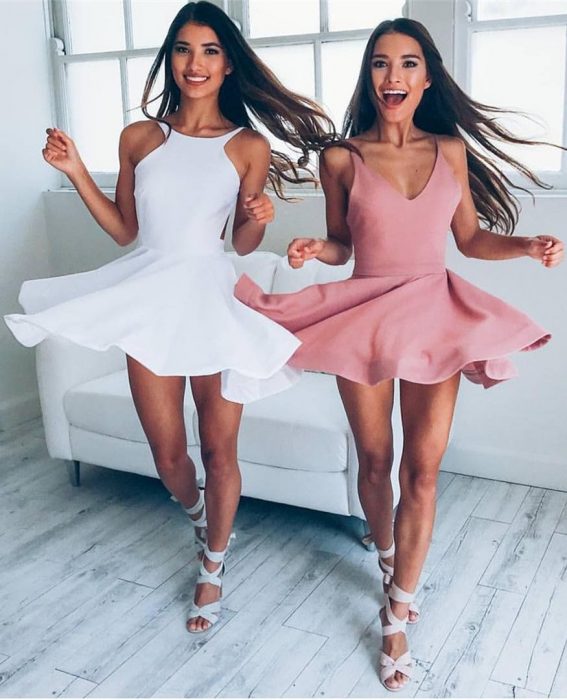 Gêmeos de cabelos castanhos com vestidos combinando, branco e rosa