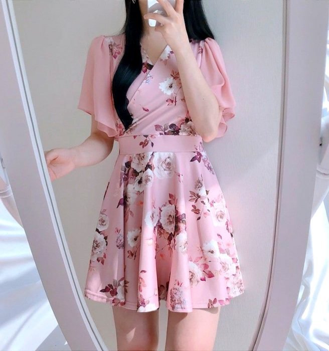 Menina tirando selfie no espelho, com vestido rosa florido curto