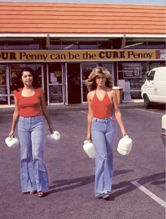 Moda feminina dos anos 70;  amigas no estacionamento saindo da loja, de jeans largos e blusa vermelha;  penteados e roupas retrô