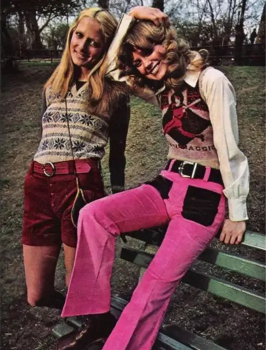 Moda feminina dos anos 70;  amigos sentados no banco do parque, suéter de malha de diamantes, shorts de veludo cotelê vermelho, calças rosa e pretas;  roupas e penteados retrô