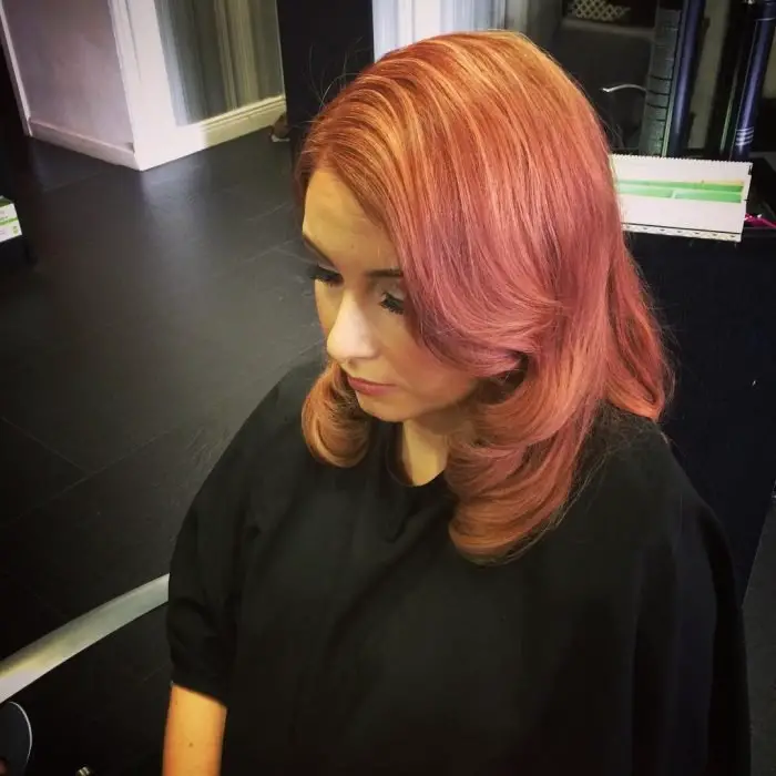 Menina com cabelo na altura dos ombros pintado de rosa com reflexos dourados e avermelhados 