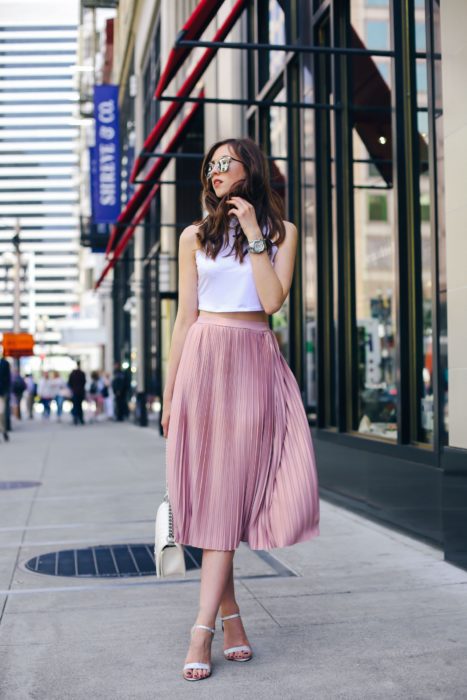Saias para o verão;  garota andando na rua, com óculos escuros, top branco e saia longa de cetim rosa