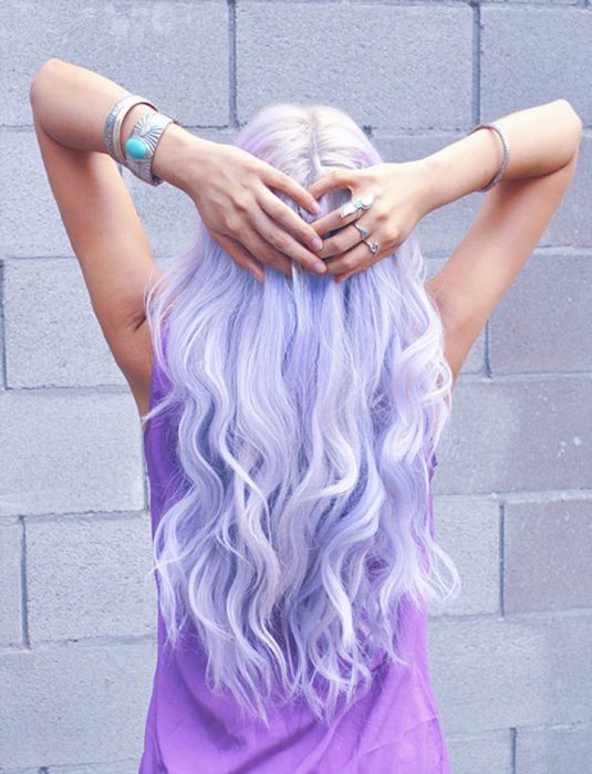 Menina com cabelo lilás segurando a cabeça 