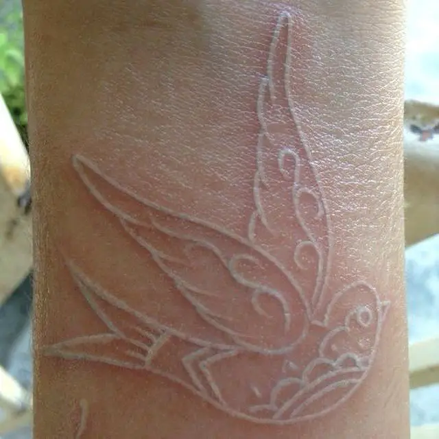 Tatuagem de pássaro feita com tinta branca 