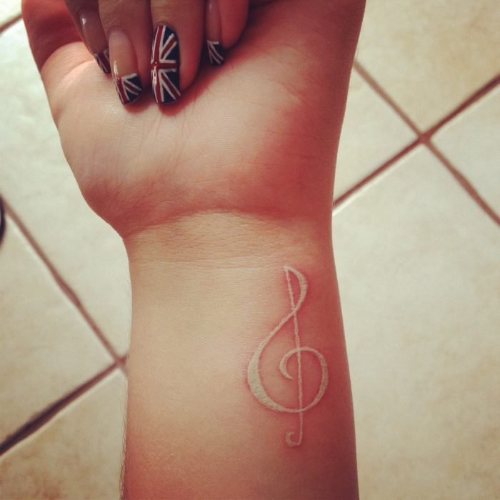Tatuagem em tinta branca em forma de letra musical 