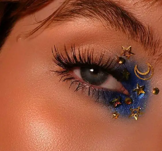 Maquiagem com sombra azul elétrica e decoração de estrela e lua