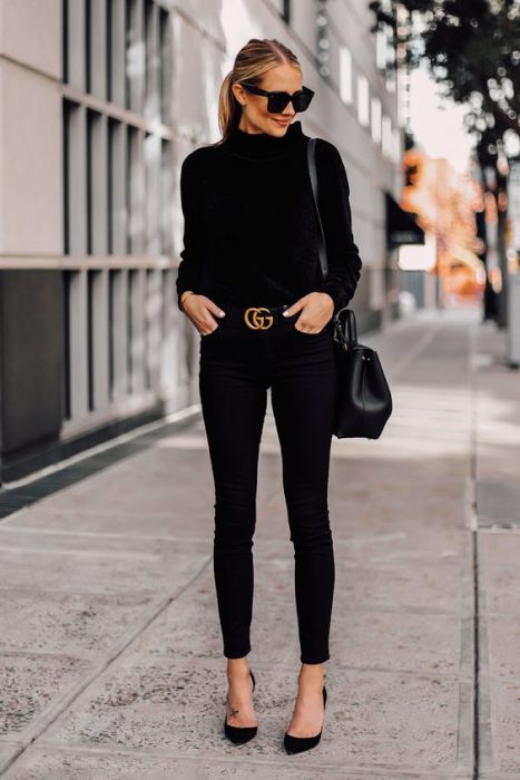 Garota na rua usando uma roupa preta de salto alto e um cinto dourado