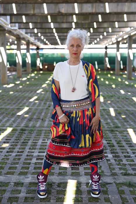 Mulher idosa vestindo jaqueta e saia com estampa tribal e tênis Nike