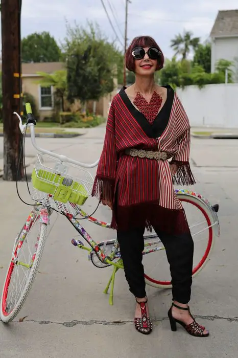 Mulher idosa vestindo uma roupa vermelha em frente a uma bicicleta 