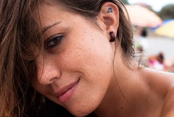 Menina com uma tatuagem atrás da orelha em forma de nota musical