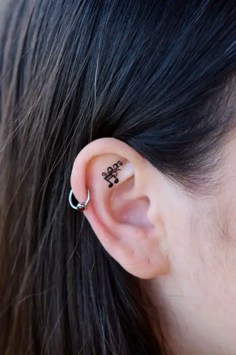 Menina com uma tatuagem atrás da orelha em forma de nota musical