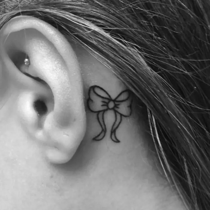 Menina com uma tatuagem atrás da orelha em forma de arco