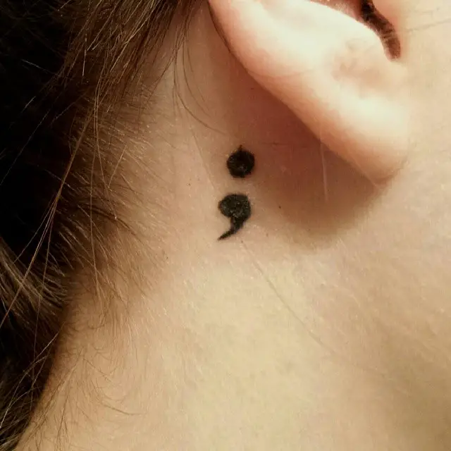Menina com uma tatuagem atrás da orelha em forma de ponto e vírgula