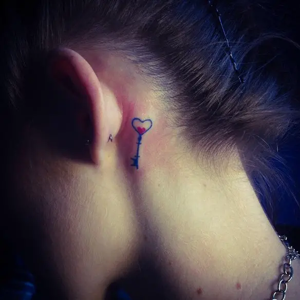 Menina com uma tatuagem atrás da orelha em forma de chave de coração 