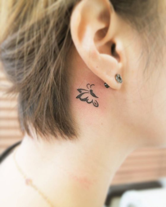 Menina com uma tatuagem atrás da orelha em forma de borboleta