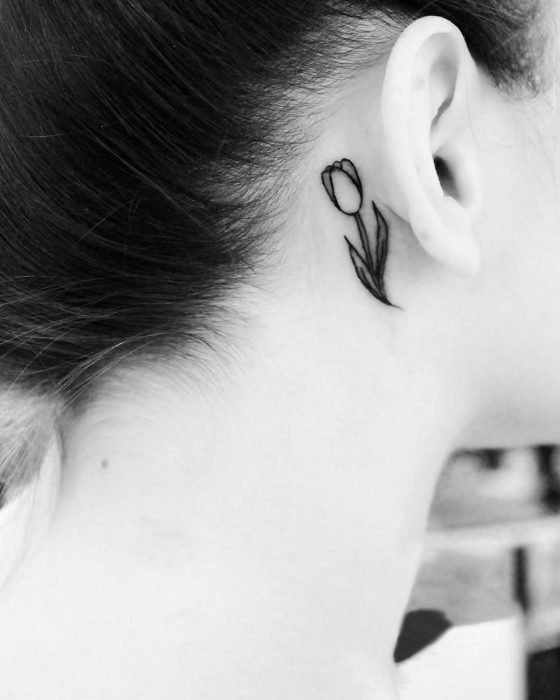 Menina com uma tatuagem atrás da orelha em forma de tulipa