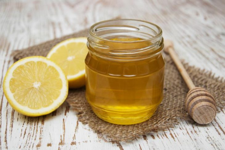 Pote de mel e rodelas de limão em uma mesa de madeira 