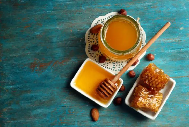 Potes de mel em uma mesa de madeira tom azul água 