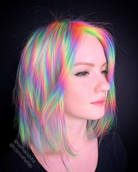 Rapariga de cabelo curto e liso, tingido em cores fantasia simulando o reflexo da luz, verde, laranja, rosa, roxo e amarelo