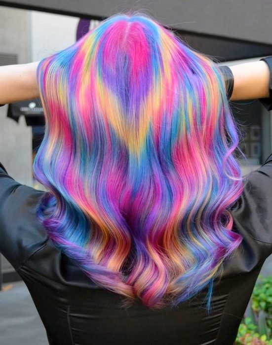 Menina com cabelo comprido pintado em cores extravagantes que parecem flashes de luz, rosa, azul, roxo e amarelo