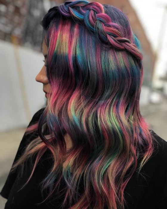 Garota de perfil com cabelo ondulado estilizado com uma trança e cores escuras fantasia, rosa, verde, azul e roxo 
