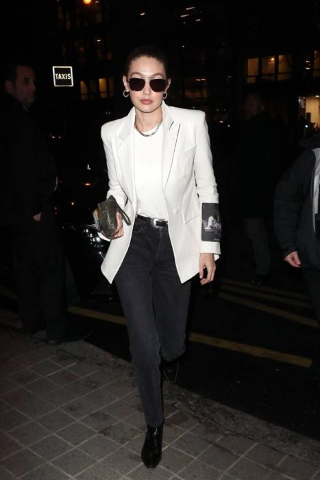 Gigi Hadid andando pelas ruas vestindo um blazer branco com jeans preto 