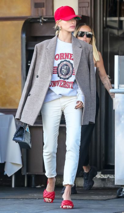 Hailey Baldwin vestindo jeans e uma blusa branca com um blazer marrom 