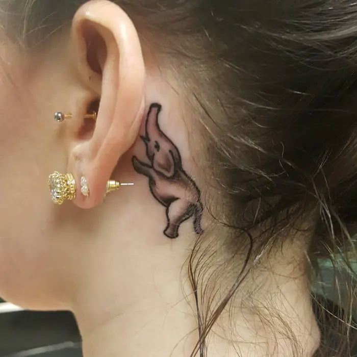 Menina com uma tatuagem atrás da orelha em forma de elefante 