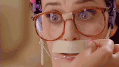 Menina de óculos e aparelho ortodôntico, com medo de remover a faixa de barbear do lábio superior, Katy Perry
