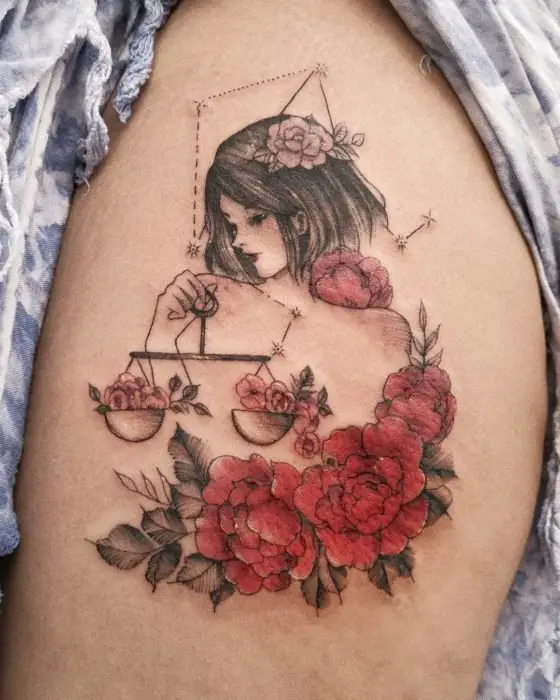 Tatuagem de uma menina segurando uma escama e flores de um lado, tinta preta e colorida na região da perna