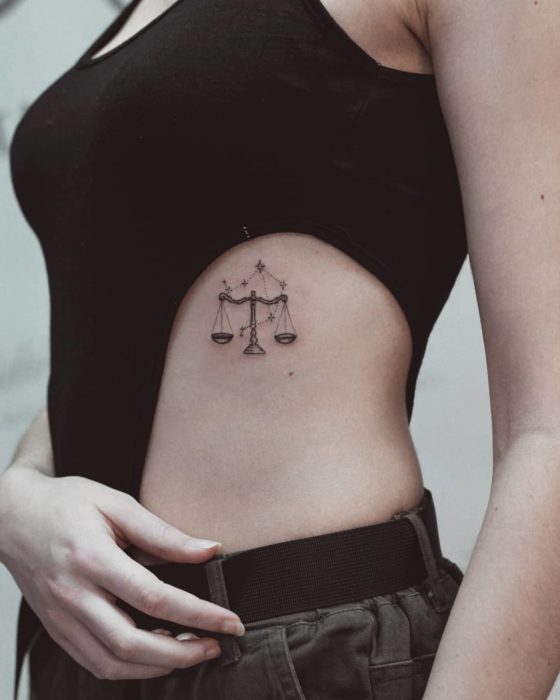 Tatuagem do símbolo de equilíbrio na área das costelas em tinta preta