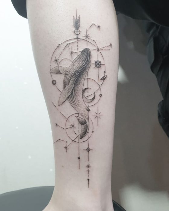 Tatuagem de constelação de Aquário com uma baleia e outros detalhes em tinta preta na área do antebraço