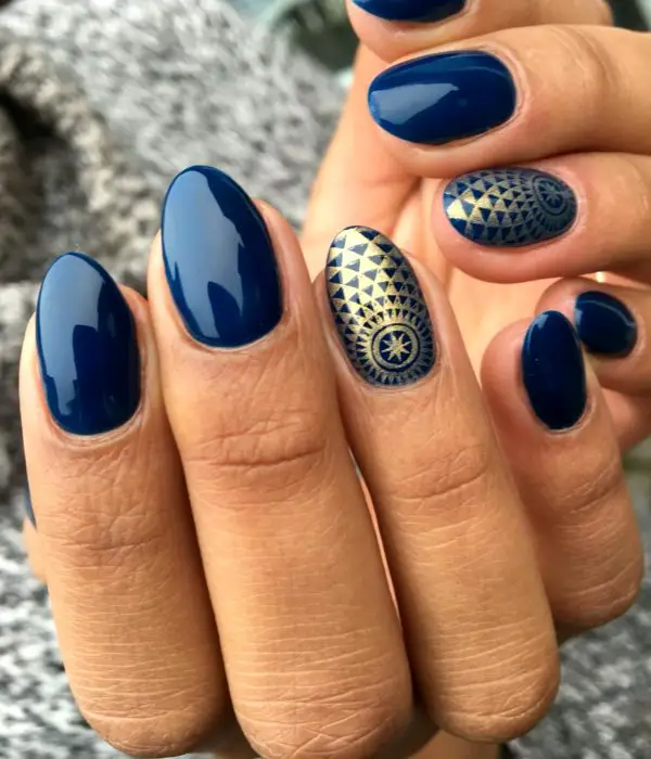 Manicure azul com figuras douradas para a festa de Reveillon;  unhas compridas em formato de amêndoa