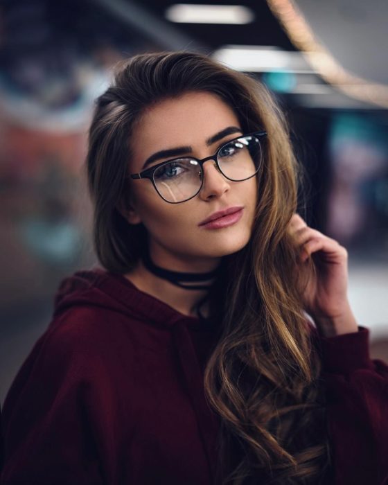 Garota posando para uma foto em que mostra seus óculos pretos 