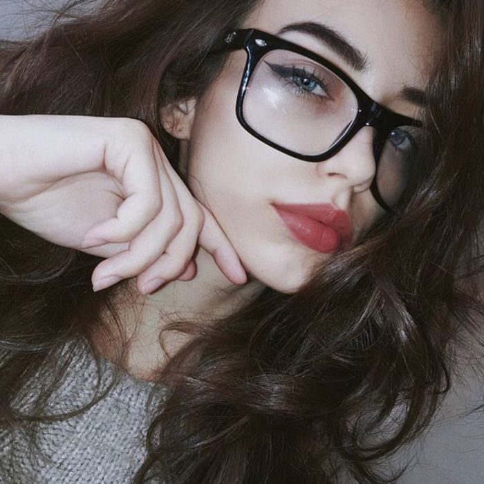 Garota posando para uma selfie em que mostra seus óculos pretos 