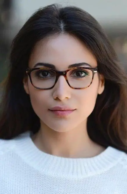 Garota posando para uma foto enquanto exibe seus pequenos óculos marrons quadrados 