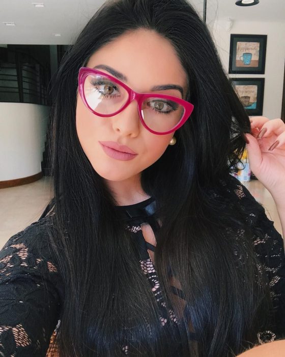 Garota posando para uma selfie enquanto mostra seus óculos rosa 